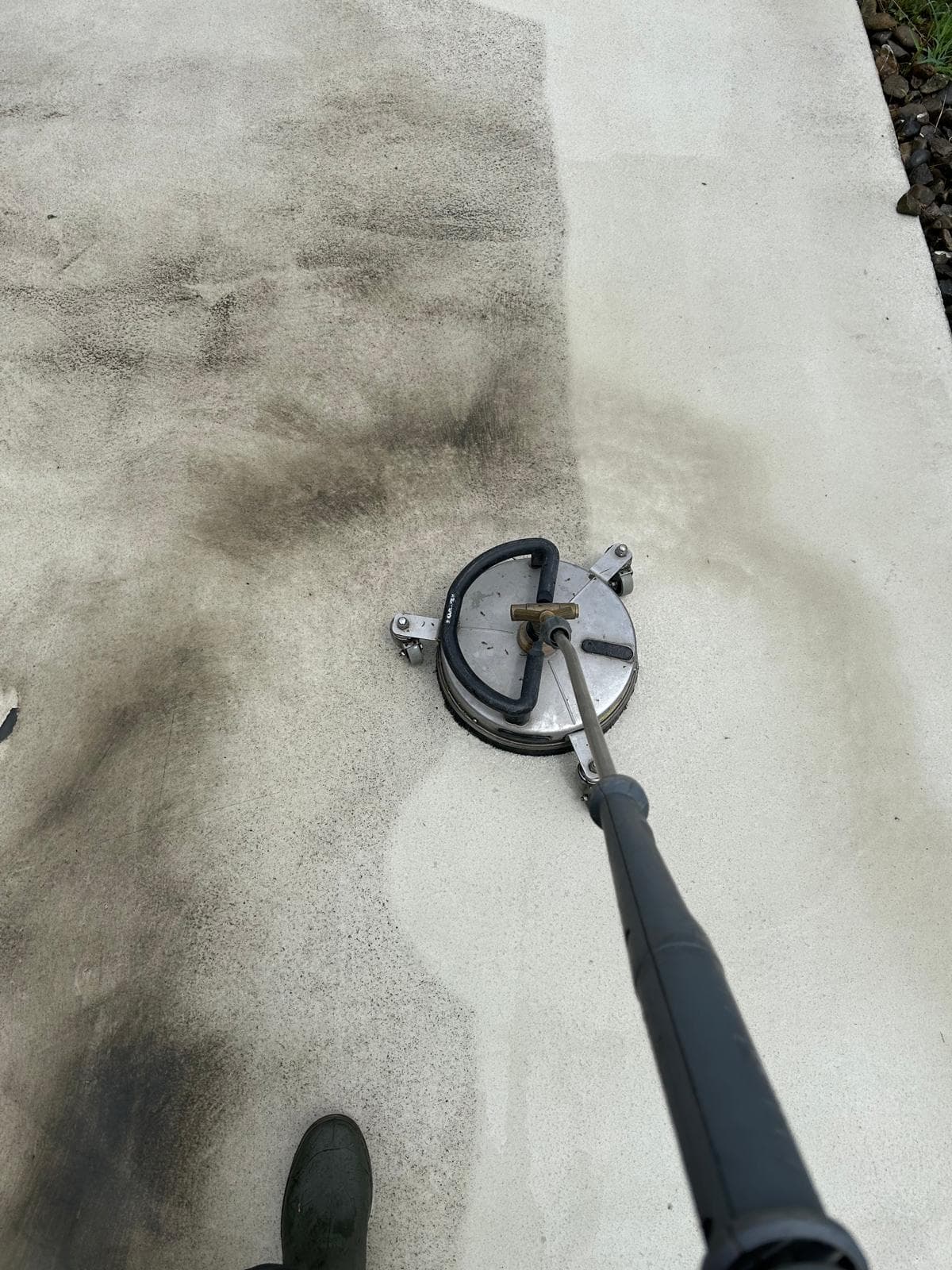 Ein Flächenreiniger auf einem Betonbelag. Der Unterschied zwischen bereits gereinigter und noch verschmutzter Fläche ist sichtbar.
