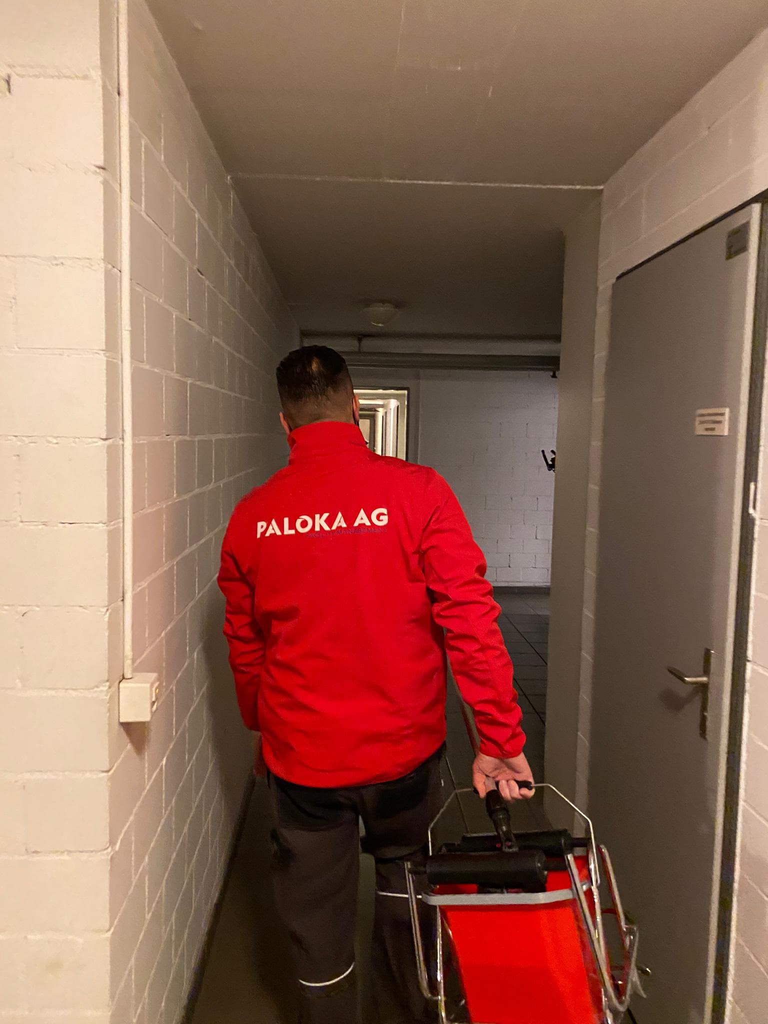 Ein Paloka-Mitarbeiter transportiert Reinigungsgeräte durch einen Korridor.