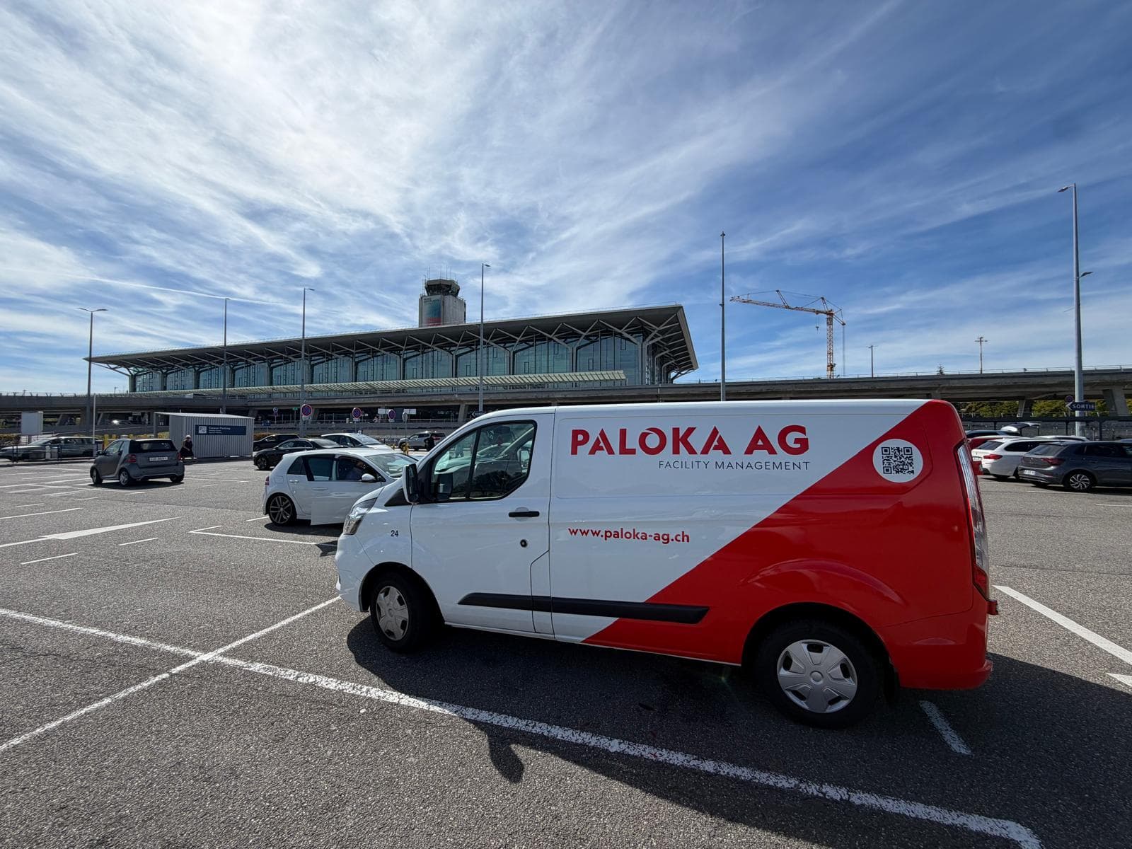 Beschriftetes Paloka-Servicefahrzeug auf einem Parkplatz vor einem grossen Gebäude.