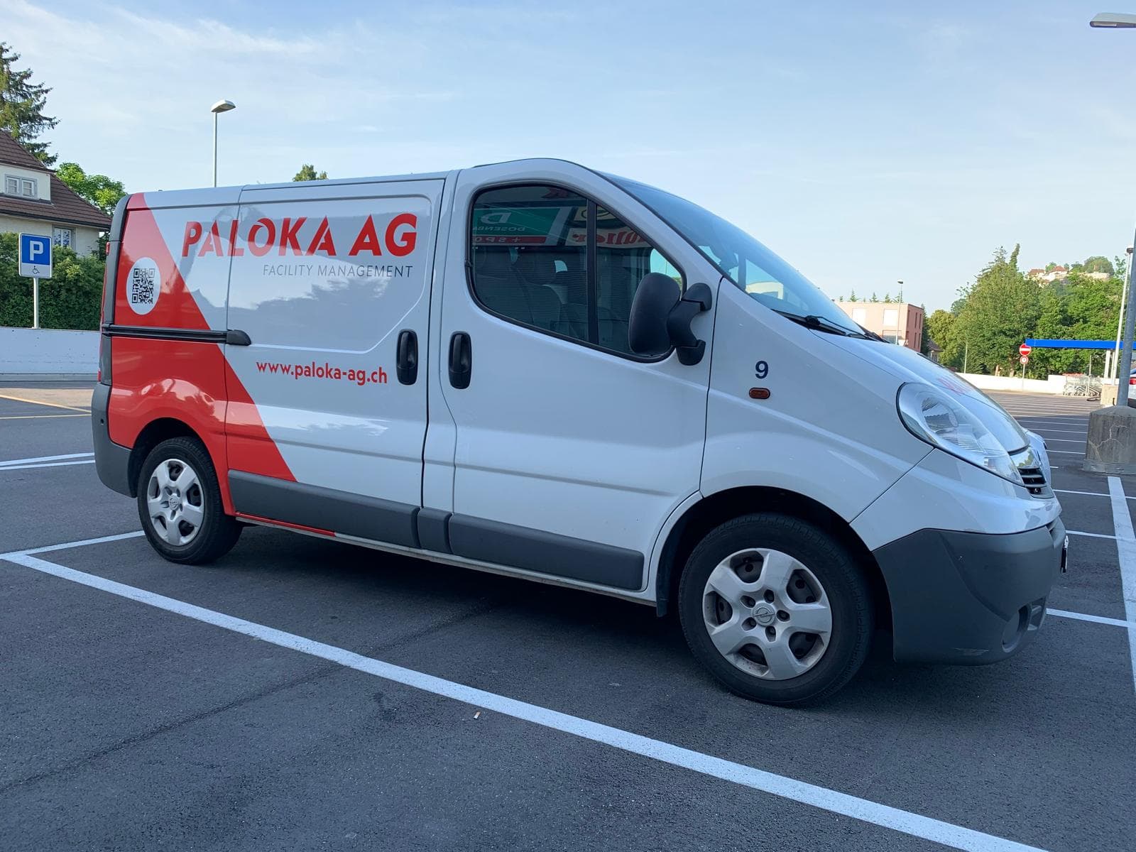Ein weisses Paloka-Servicefahrzeug mit roter Firmenbeschriftung auf einem Parkplatz.