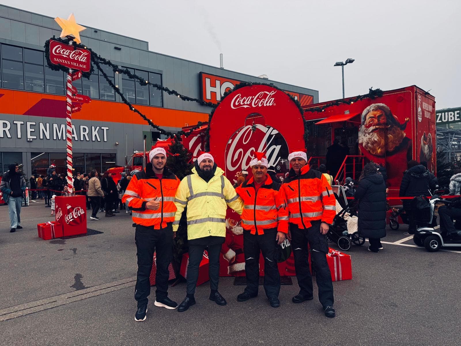 Vier Teammitglieder in Warnkleidung und Weihnachtsmützen vor einem weihnachtlich gestalteten Veranstaltungsbereich.