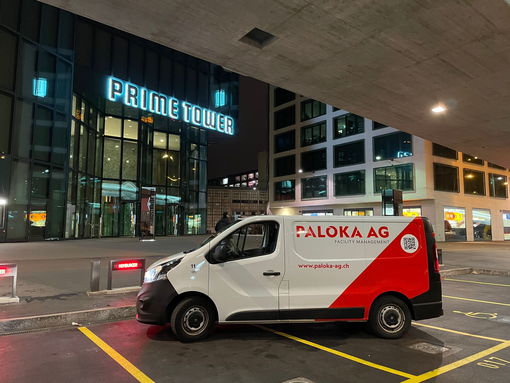 Ein beleuchteter Paloka-Servicebus am Abend vor dem Prime Tower in Zürich.